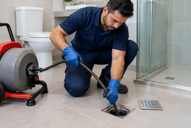 Especialista desentupindo um ralo em uma residência.